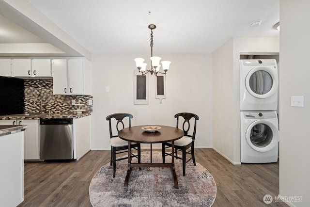 kitchen with dishwasher, stacked washer / drying machine, a chandelier, decorative backsplash, and white cabinetry