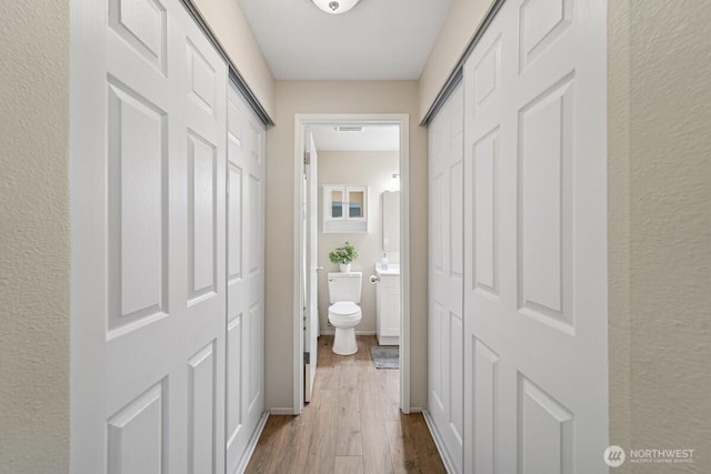 bathroom featuring wood finished floors, vanity, toilet, and a textured wall