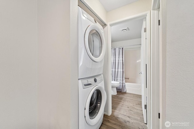 washroom featuring stacked washer / drying machine and wood finished floors