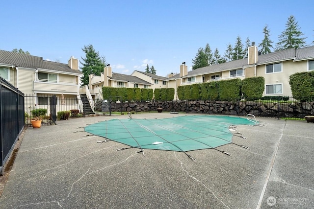 community pool featuring fence, a residential view, and a patio area