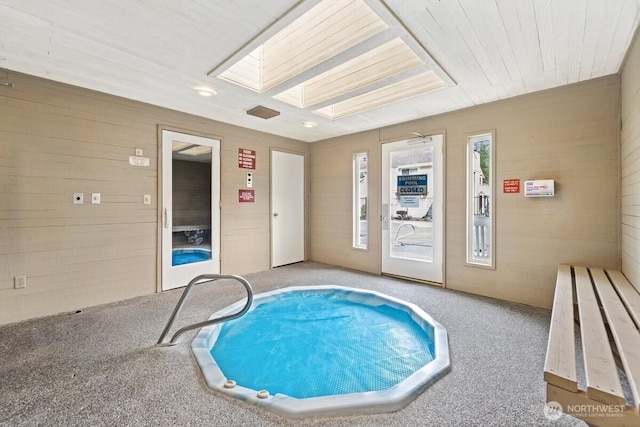 view of swimming pool with a skylight and a hot tub