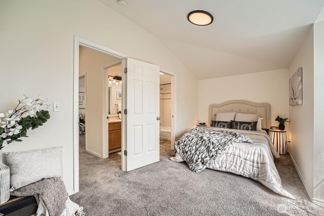 bedroom with light carpet, vaulted ceiling, ensuite bathroom, and baseboards