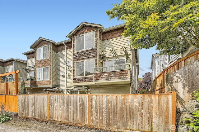 rear view of property with fence and a balcony