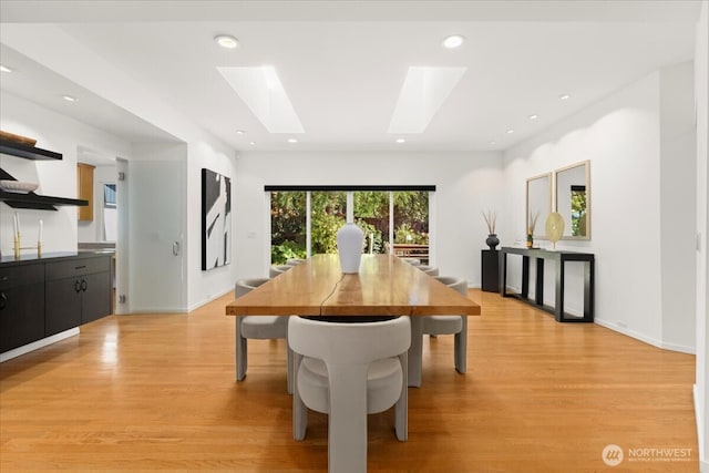 dining space with a skylight, light wood-style floors, and recessed lighting