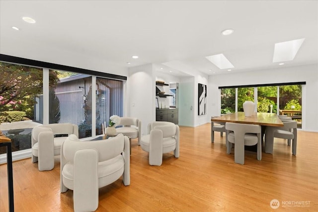 living area with a skylight, light wood-type flooring, and recessed lighting