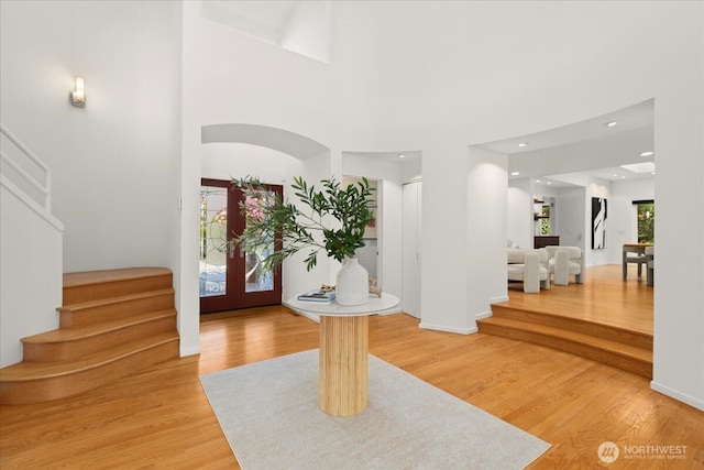 entryway with stairway, light wood-style flooring, a high ceiling, french doors, and recessed lighting