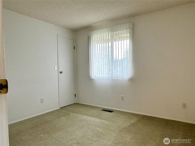 carpeted empty room with a textured ceiling and baseboards
