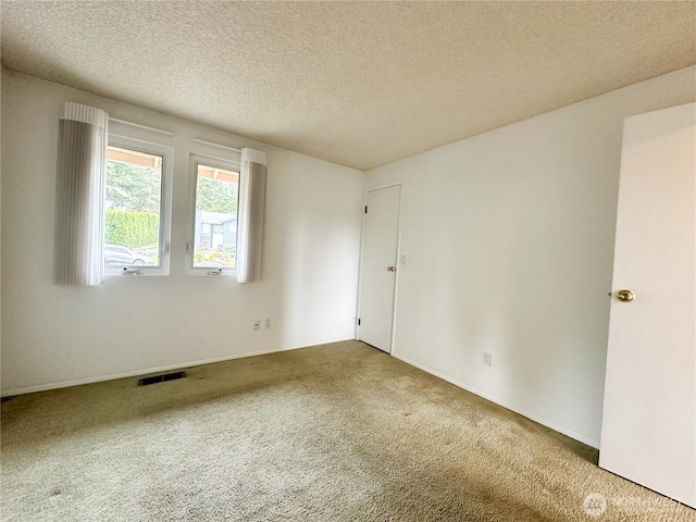 carpeted empty room with a textured ceiling