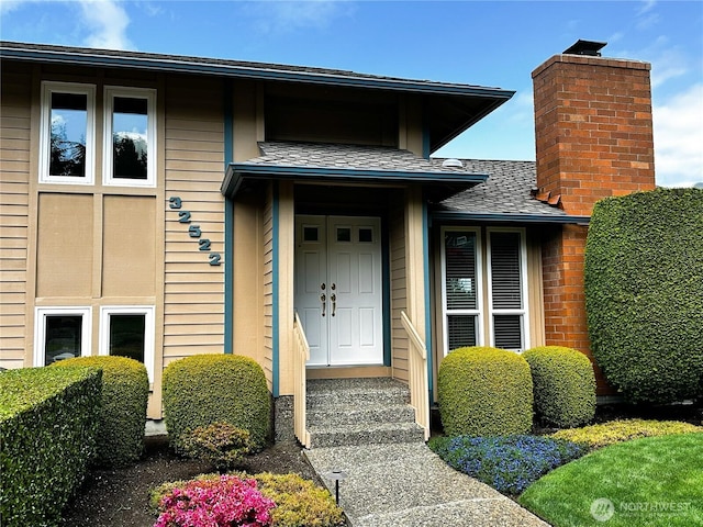 property entrance with a chimney and a shingled roof