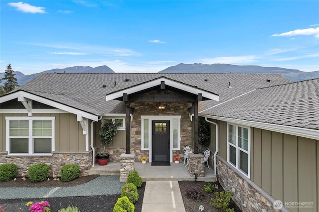 view of front facade with stone siding, board and batten siding, a mountain view, and a shingled roof