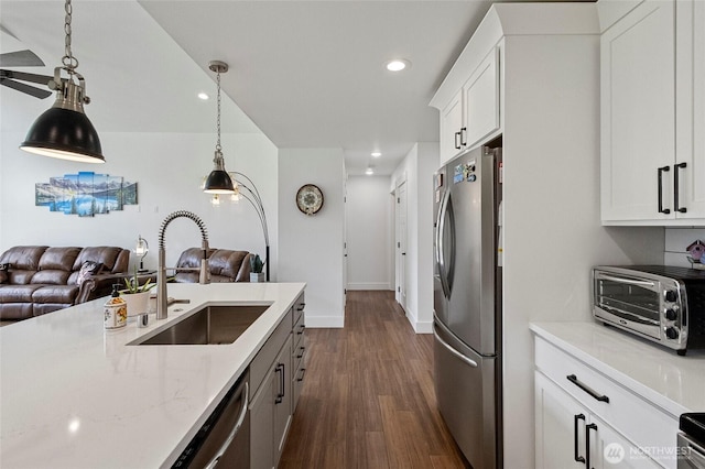 kitchen featuring appliances with stainless steel finishes, a sink, open floor plan, dark wood-style floors, and white cabinets