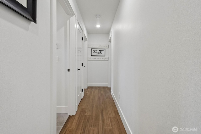 corridor with dark wood-style flooring, baseboards, and recessed lighting