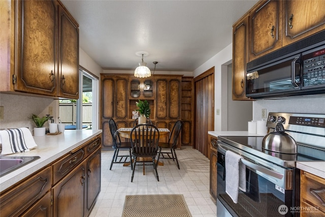 1102 S Villard St, Tacoma, WA 98465 - kitchen featuring stainless steel range with electric stovetop, black microwave, light countertops, decorative light fixtures, and a sink