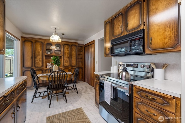 1102 S Villard St, Tacoma, WA 98465 - kitchen featuring stainless steel electric stove, black microwave, light countertops, pendant lighting, and brown cabinetry