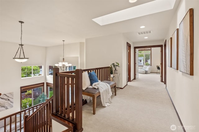 hallway with light carpet, a chandelier, an upstairs landing, a skylight, and recessed lighting