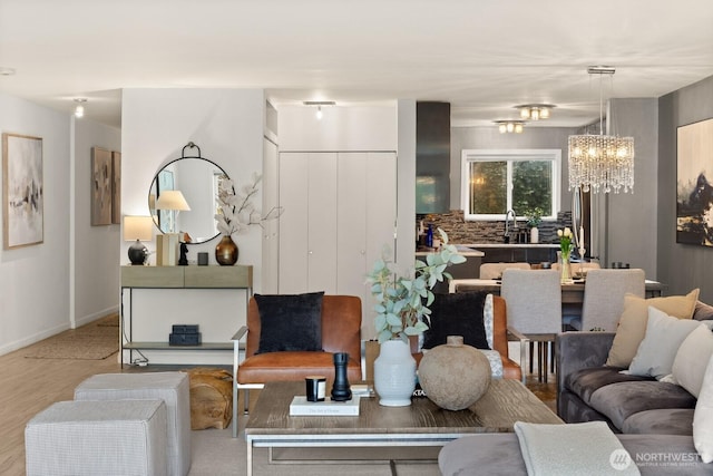 living area with a chandelier, light wood-style flooring, and baseboards