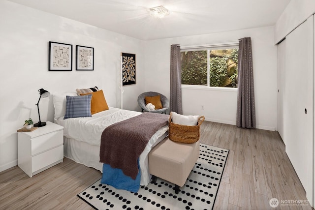 bedroom featuring light wood-style floors, baseboards, and a closet