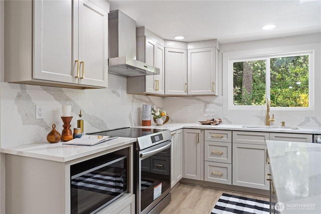 2419 Rocky Point Rd NW, Bremerton, WA 98312 - kitchen featuring wall chimney exhaust hood, stainless steel electric stove, a sink, light wood finished floors, and backsplash