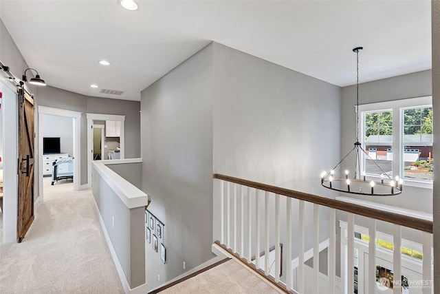 191 E Sterling Dr, Allyn, WA 98524 - hallway featuring a barn door, a chandelier, an upstairs landing, light colored carpet, and recessed lighting
