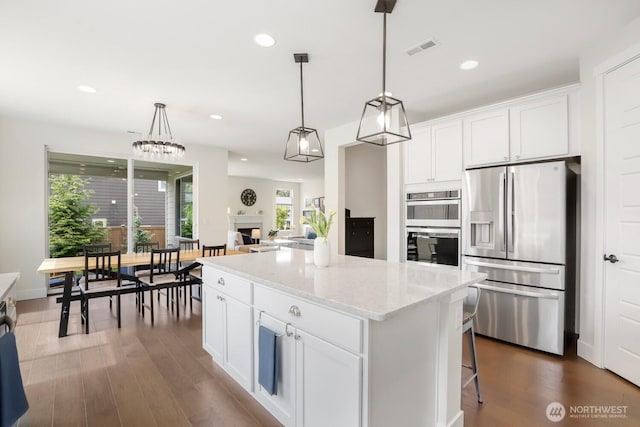 28611 NE 155th St, Duvall, WA 98019 - kitchen with appliances with stainless steel finishes, a center island, white cabinets, dark wood-type flooring, and light stone countertops