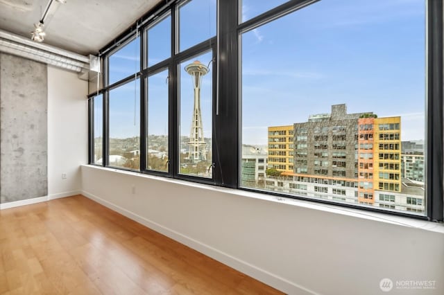 empty room with wood finished floors, baseboards, and a city view