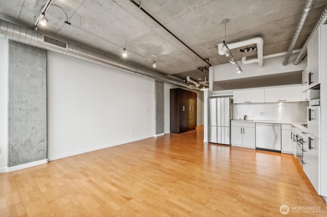 interior space featuring appliances with stainless steel finishes, light wood-style flooring, white cabinetry, a sink, and light countertops