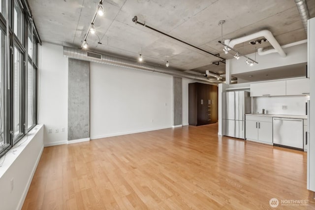 unfurnished living room featuring light wood finished floors, baseboards, and a sink