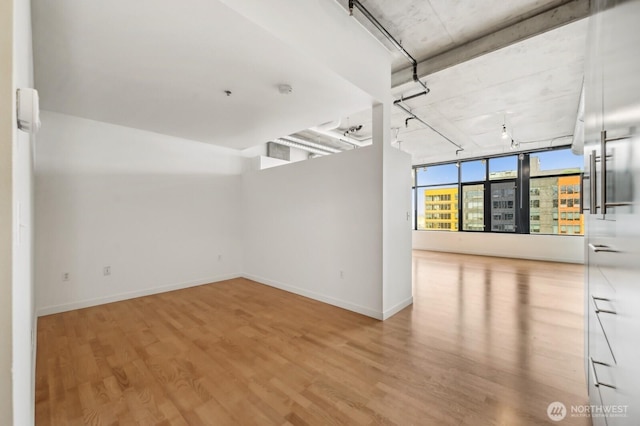spare room featuring wood finished floors, baseboards, and rail lighting