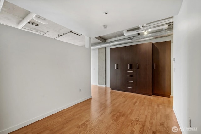 spare room with light wood finished floors, baseboards, track lighting, and fire sprinkler in ceiling