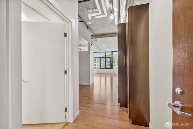 corridor with light wood-style floors and baseboards