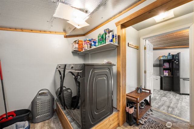 clothes washing area with washing machine and dryer and wood finished floors