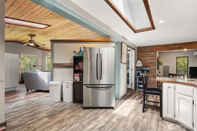kitchen with freestanding refrigerator, white cabinetry, vaulted ceiling, light wood-style flooring, and ceiling fan
