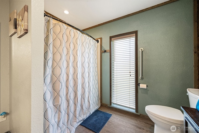 bathroom with toilet, a textured wall, wood finished floors, and a shower with shower curtain