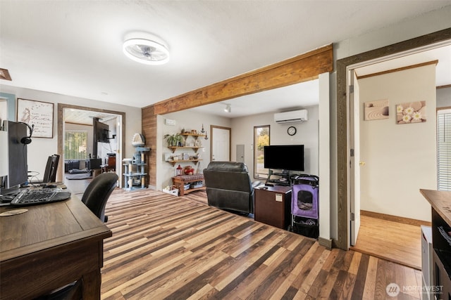 office area with a wall mounted AC, wood finished floors, baseboards, and beam ceiling