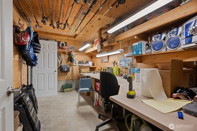 office with concrete floors, a workshop area, and wooden walls