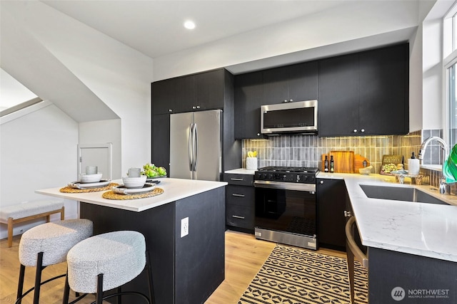 9752A Holman Rd NW, Seattle, WA 98117 - kitchen with dark cabinetry, stainless steel appliances, a sink, a kitchen island, and a kitchen breakfast bar