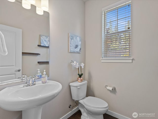 bathroom featuring baseboards, toilet, a sink, and wood finished floors