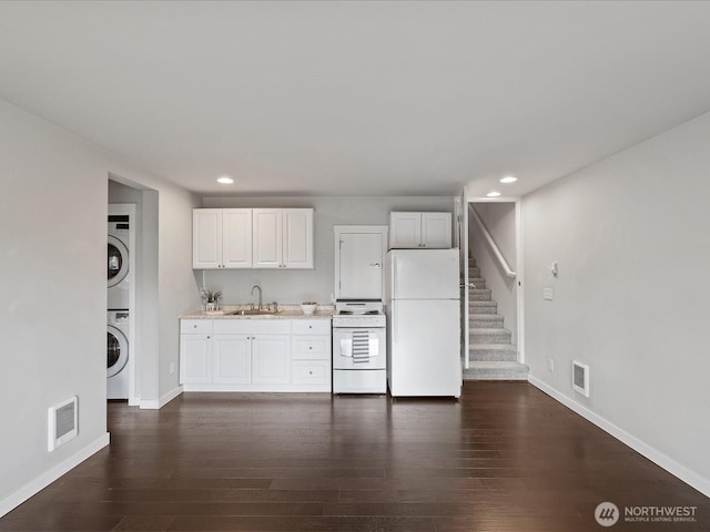 kitchen featuring white appliances, a sink, stacked washer / drying machine, recessed lighting, and baseboards