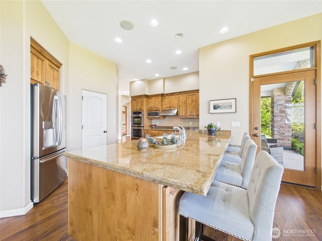 8144 Todderjen Ln SW, Olympia, WA 98512 - kitchen with stainless steel appliances, light stone counters, dark wood-style floors, a kitchen breakfast bar, and recessed lighting