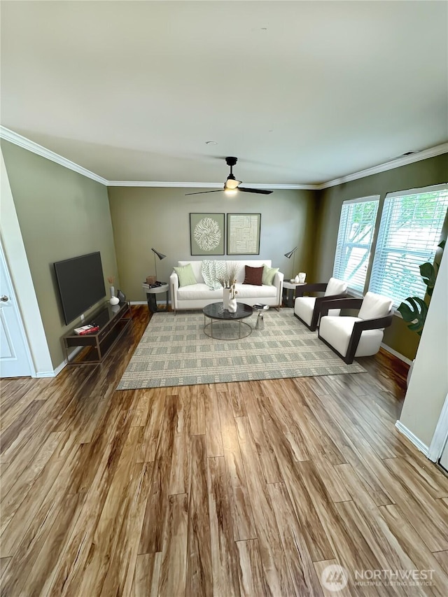 living area featuring ornamental molding, wood finished floors, ceiling fan, and baseboards