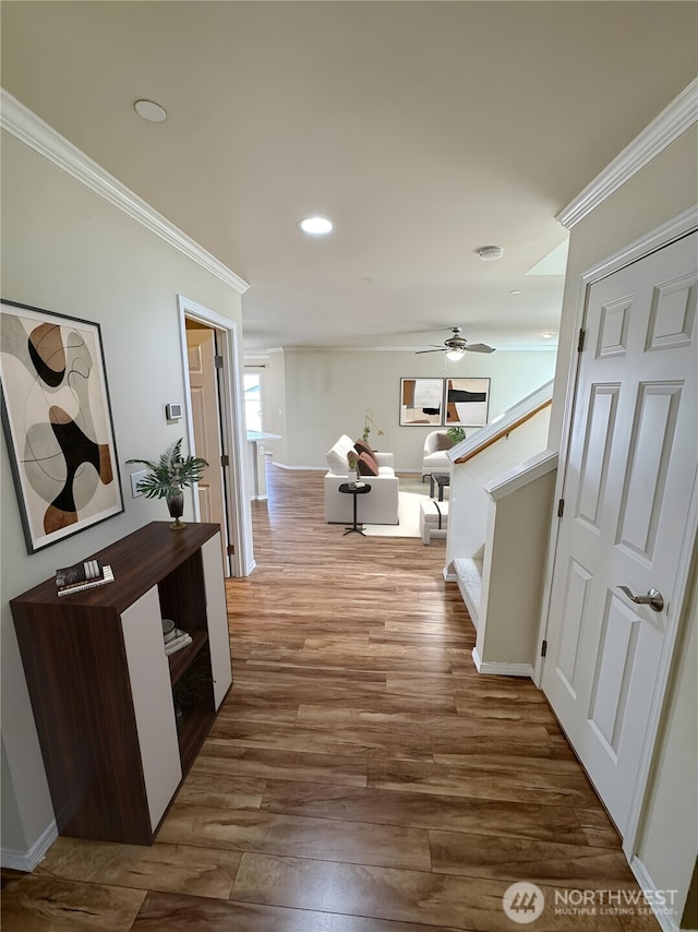 corridor with ornamental molding, wood finished floors, stairway, and recessed lighting
