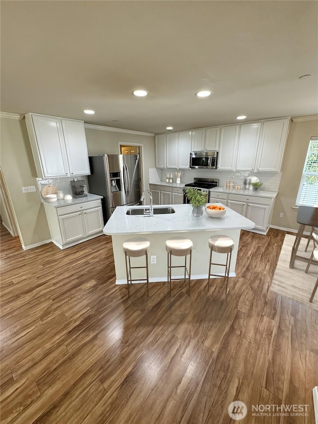 kitchen with stainless steel appliances, a sink, white cabinets, tasteful backsplash, and crown molding