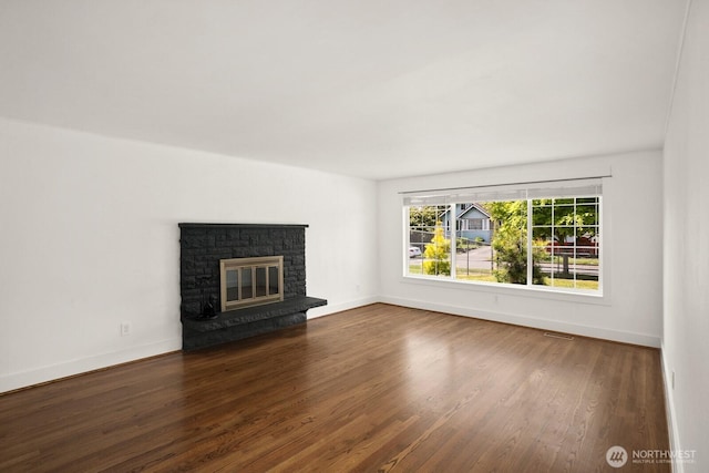 unfurnished living room with wood finished floors, baseboards, and a glass covered fireplace