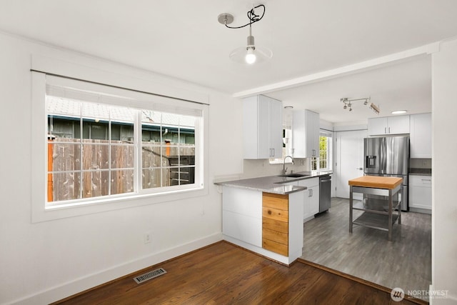 kitchen featuring stainless steel appliances, a sink, baseboards, dark wood finished floors, and white cabinetry