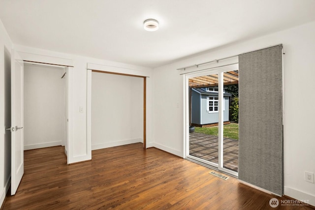 unfurnished bedroom with access to outside, wood finished floors, and baseboards