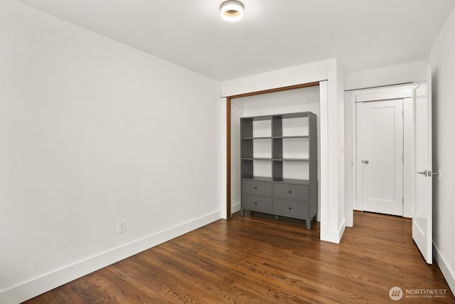 unfurnished bedroom featuring baseboards, wood finished floors, and a closet