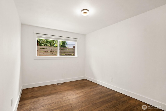 empty room featuring dark wood-style flooring and baseboards