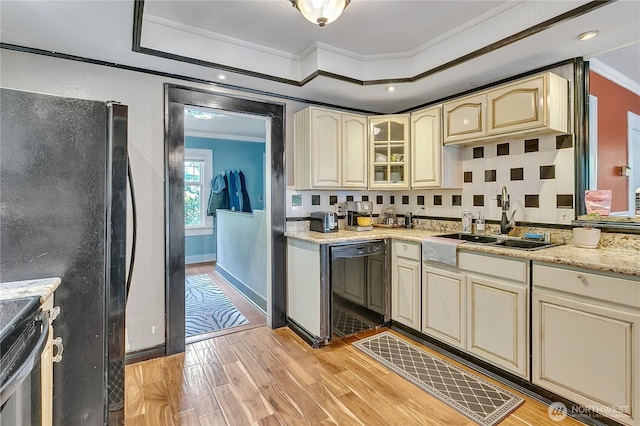 kitchen featuring ornamental molding, cream cabinetry, a sink, black appliances, and light wood-style flooring