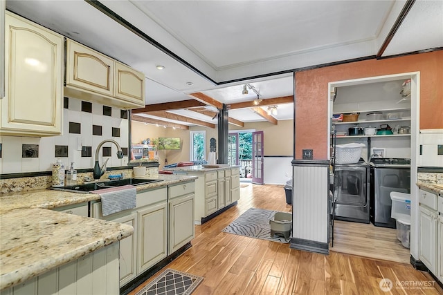 kitchen featuring washing machine and clothes dryer, cream cabinets, a sink, and beamed ceiling