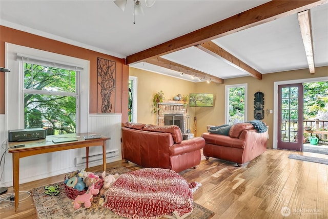 living room featuring a baseboard heating unit, light wood-style flooring, beam ceiling, a fireplace, and ceiling fan